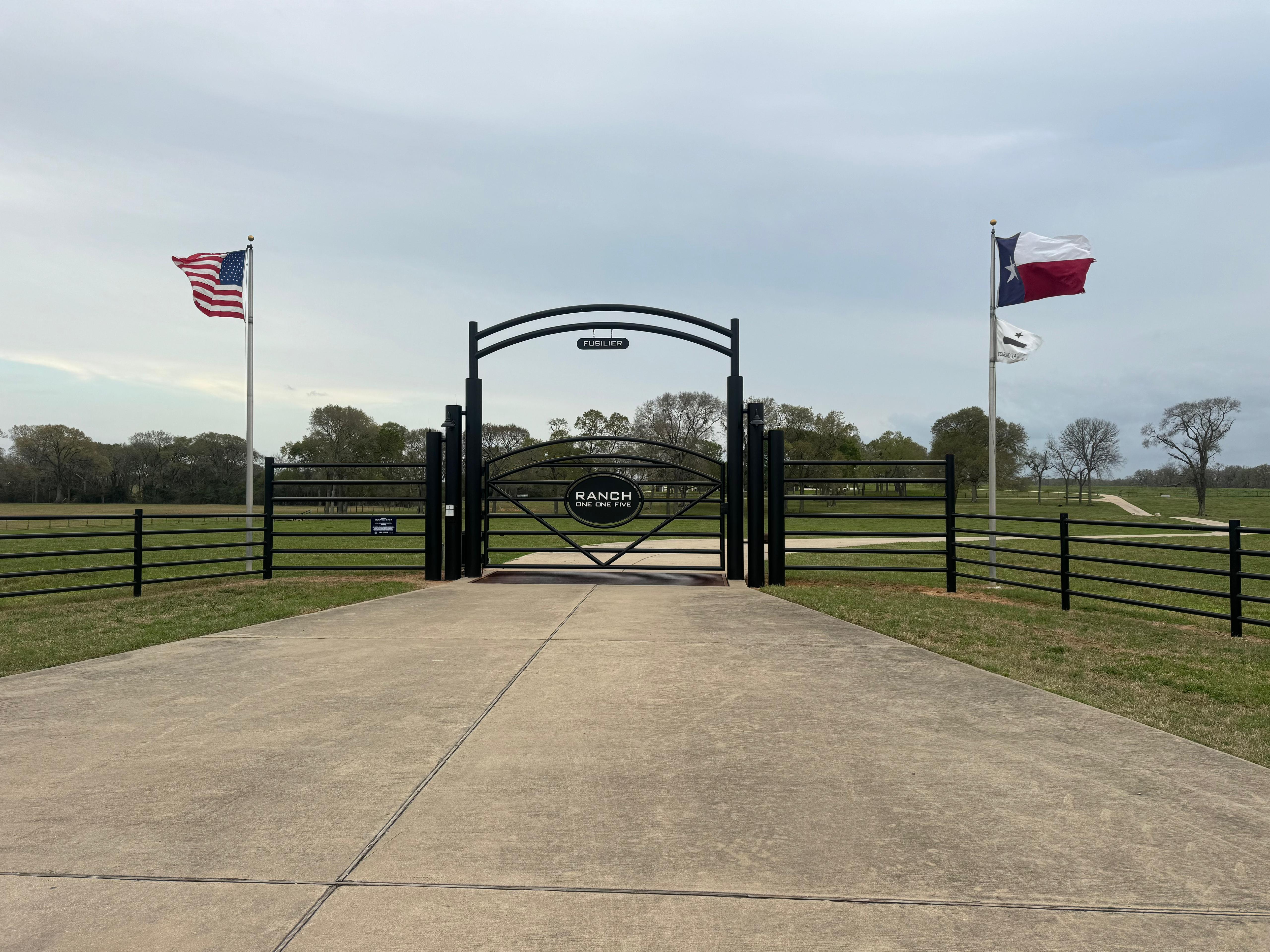 Custom ranch entrance gate with Texas and United States flags