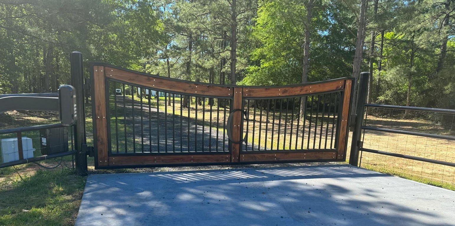 Wood and steel automatic driveway gate at a wooded property